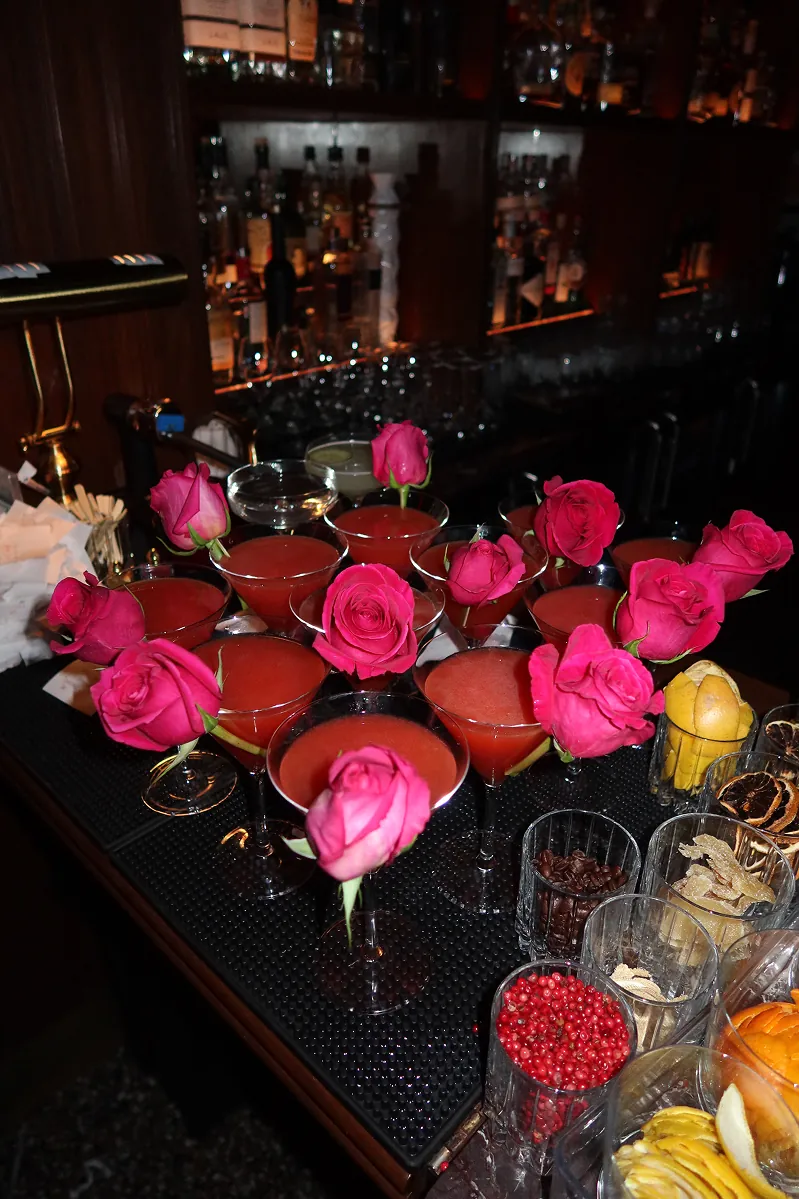 A lineup of rose-topped pink cocktails displayed at the Beefbar NYC bar, surrounded by fresh citrus and garnishes for a romantic Galentine’s celebration.