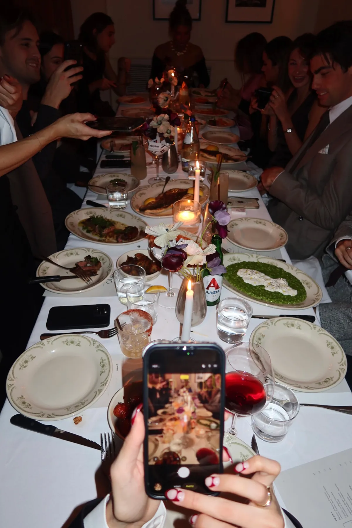 @jessworkk capturing a long candlelit dinner table at Opto for Friendsgiving as plates of shared dishes and cocktails are passed around.