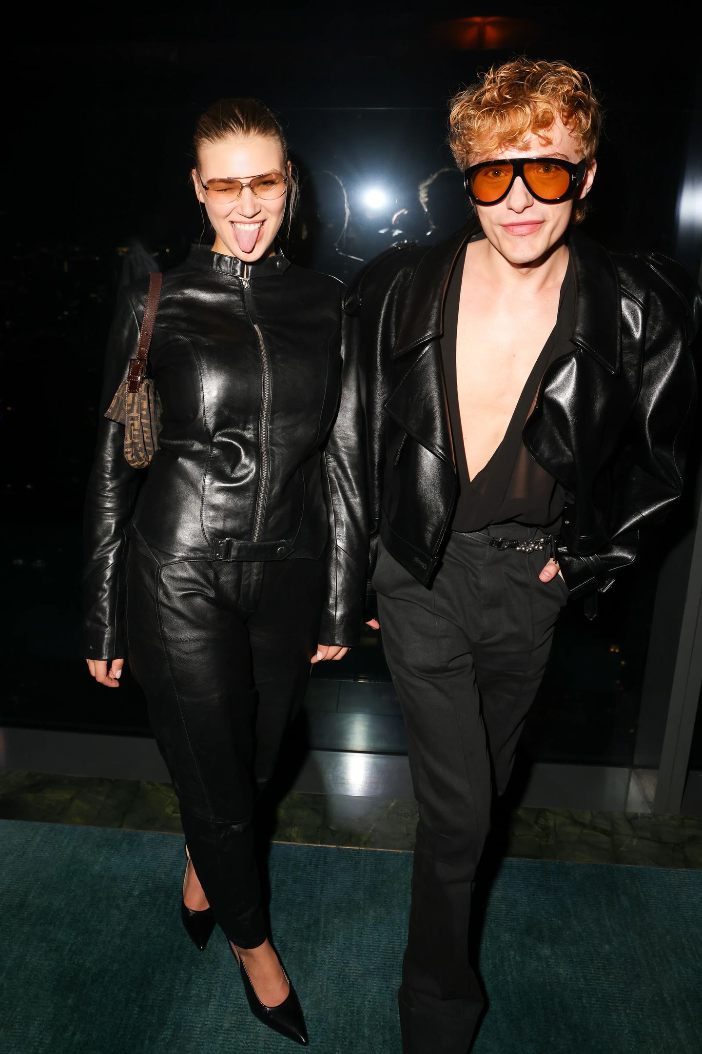 Two stylish guests in all-black leather and tinted sunglasses posing at the Made in New York event by Contra and Storytime at Nubeluz, NYC.