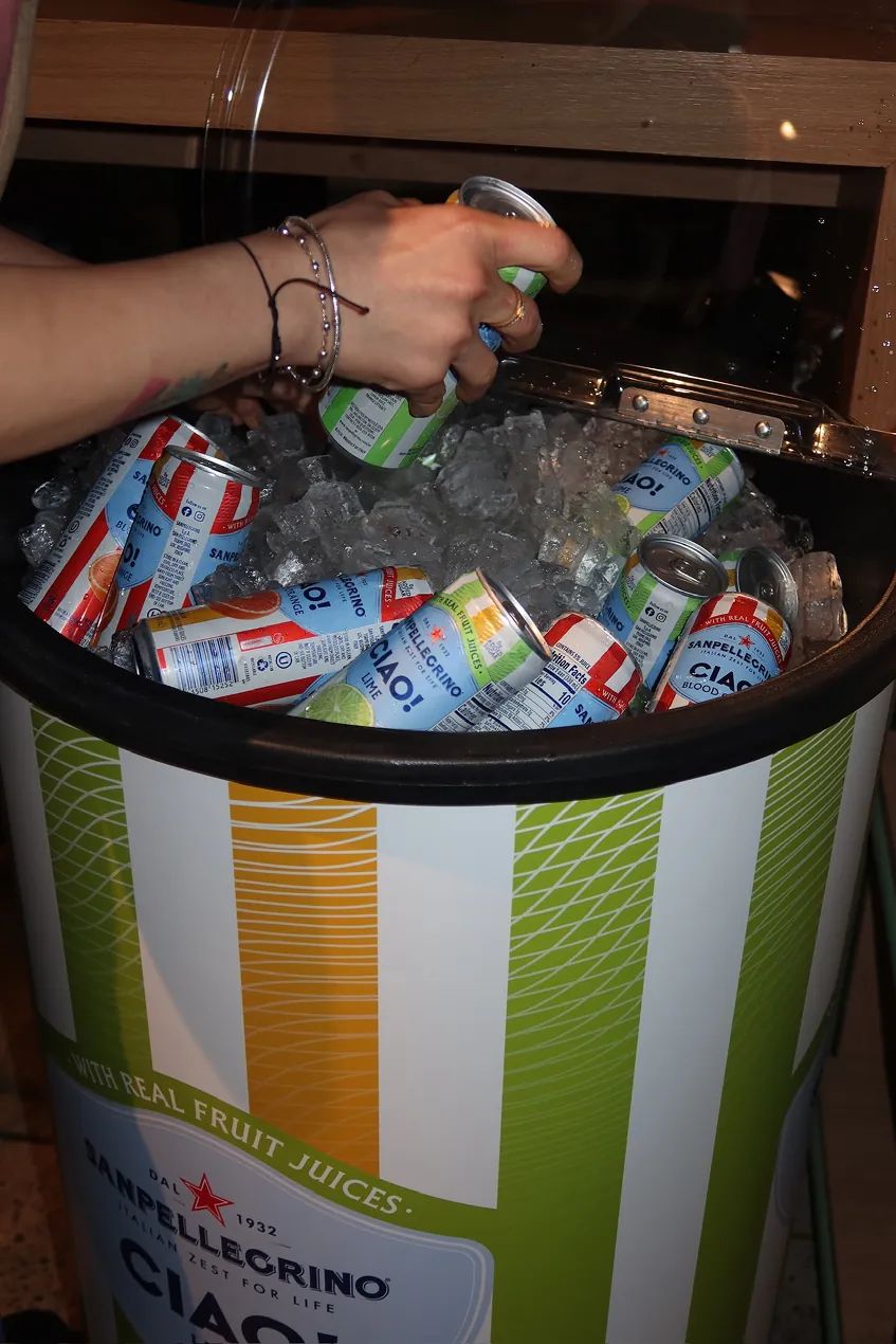 Guests grab chilled Sanpellegrino Ciao! drinks from an ice-filled cooler during the Storytime celebration at the Carrot Express NoLita opening in NYC.