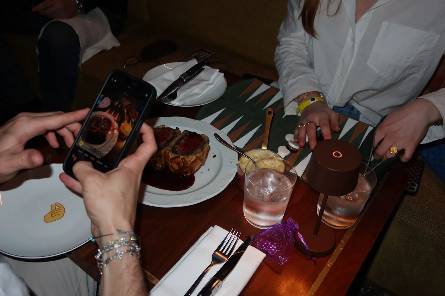 Guests photograph food and play backgammon during the Storytime x Backgammon Social event at Beefbar NYC, featuring cocktails, dining, and networking.