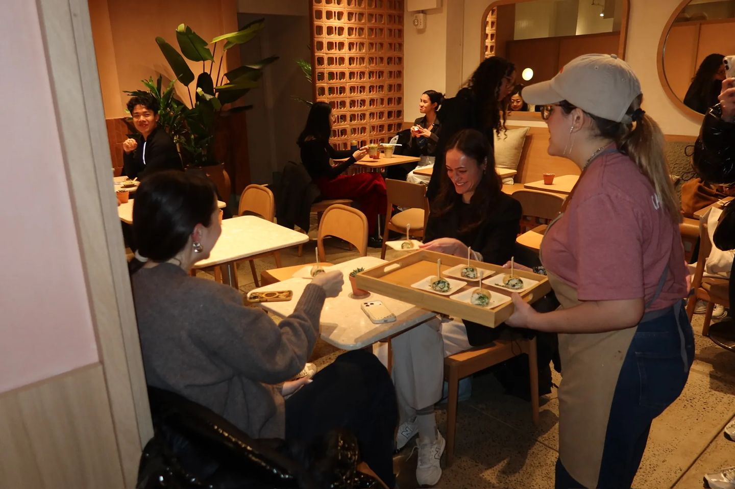 Guests gather and enjoy bites during the Storytime celebration at the new Carrot Express NoLita location, as staff serve food and drinks in the warm café space.