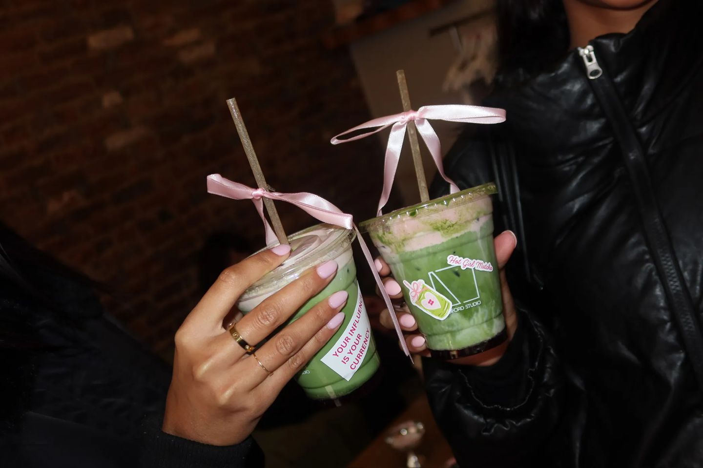 Guests hold signature Hot Girl Matcha drinks with pink ribbon details during the Storytime x Bedford Studios NYC collaboration event in the West Village.