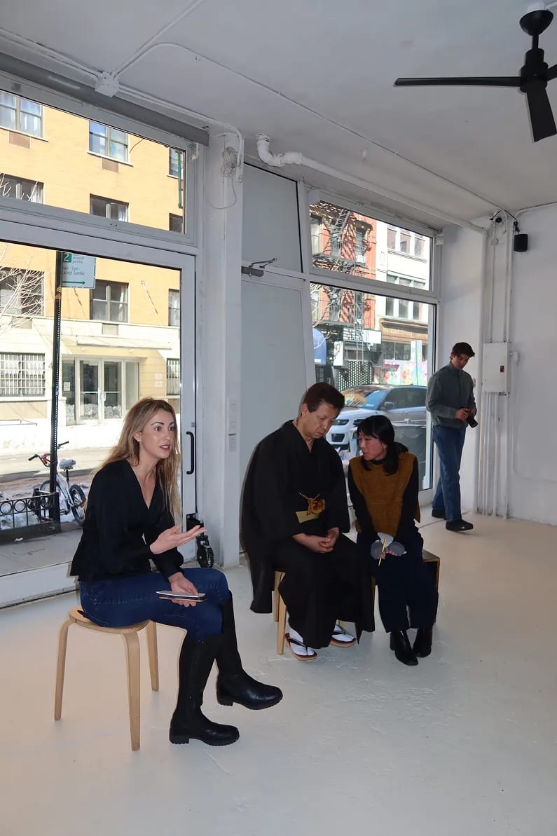 Guests gather inside a bright, minimalist space during a Matchaful x Storytime event. A woman speaks while seated on a stool as attendees chat nearby, with natural light coming through large windows overlooking a city street.