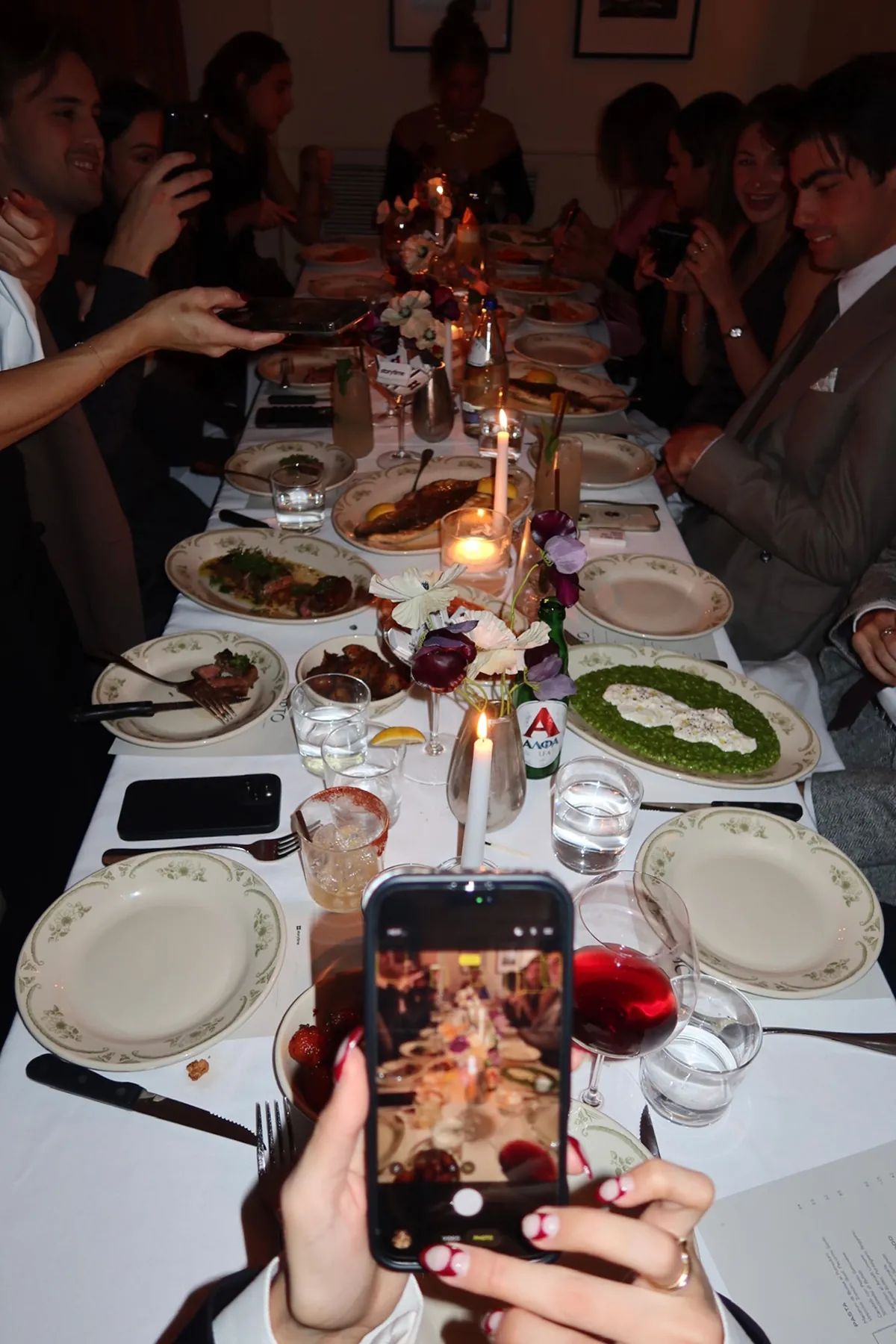 @jessworkk capturing a long candlelit dinner table at Opto for Friendsgiving as plates of shared dishes and cocktails are passed around.
