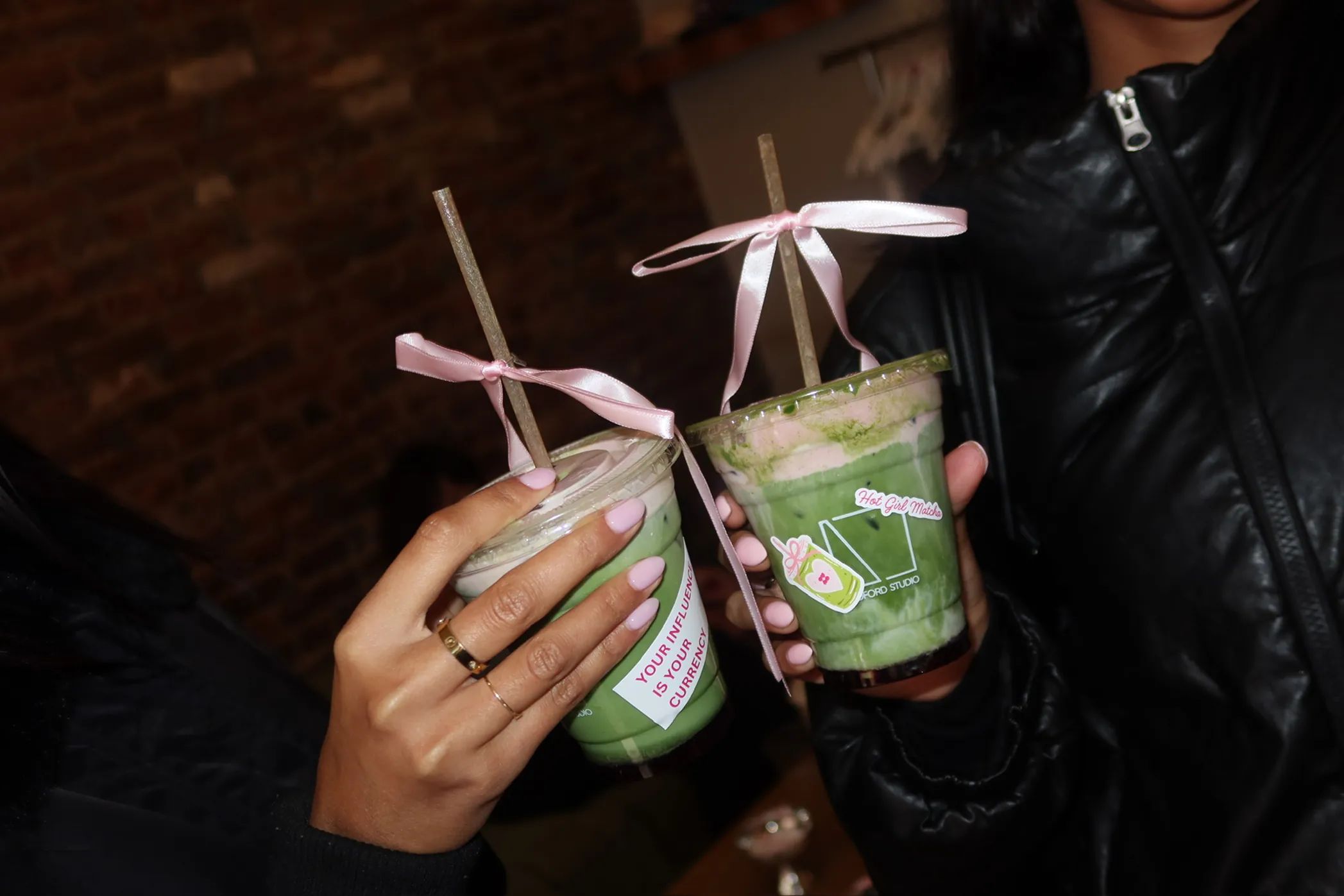Guests hold signature Hot Girl Matcha drinks with pink ribbon details during the Storytime x Bedford Studios NYC collaboration event in the West Village.