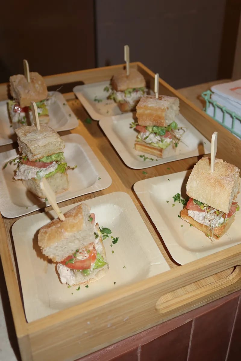 Six mini chicken salad ciabatta sandwiches on bamboo plates at the Carrot Express creator event