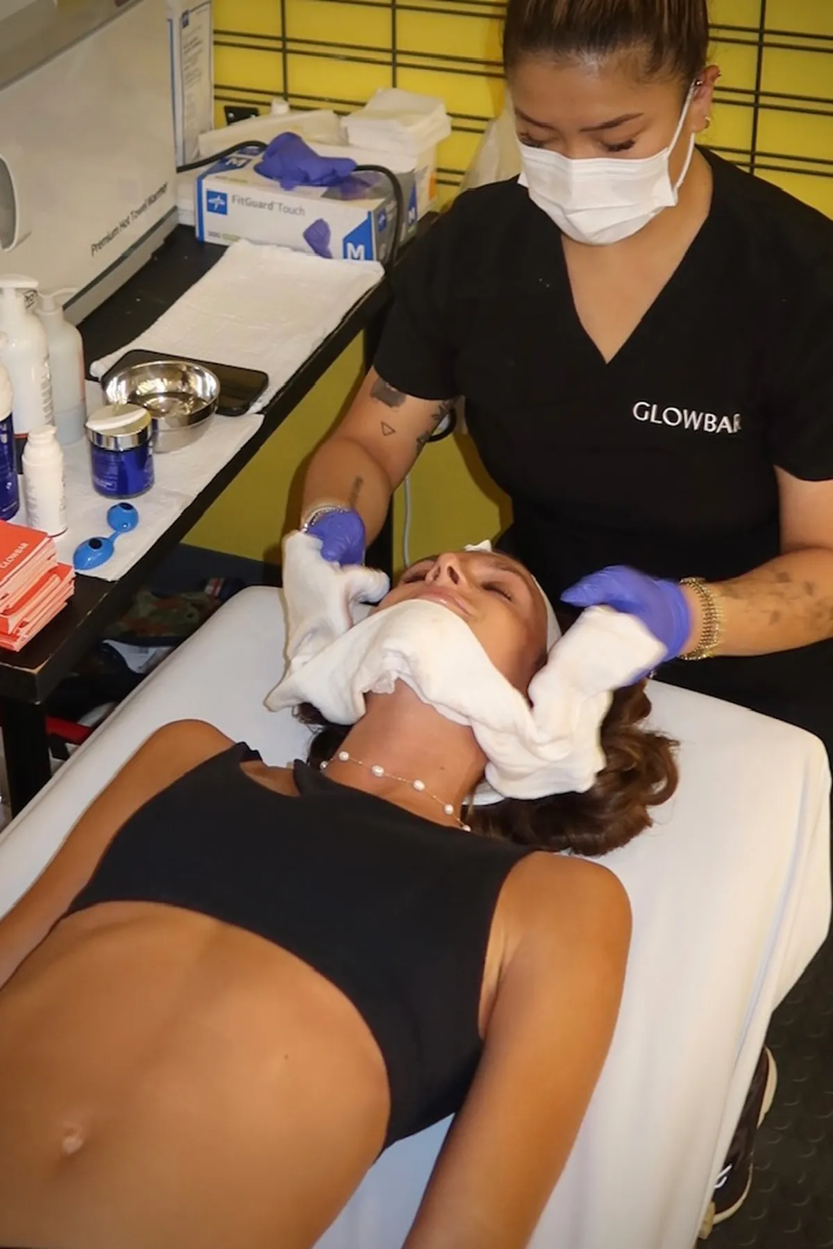 A Glowbar aesthetician wearing a mask and gloves giving a facial treatment to @nycbutglutenfree. 