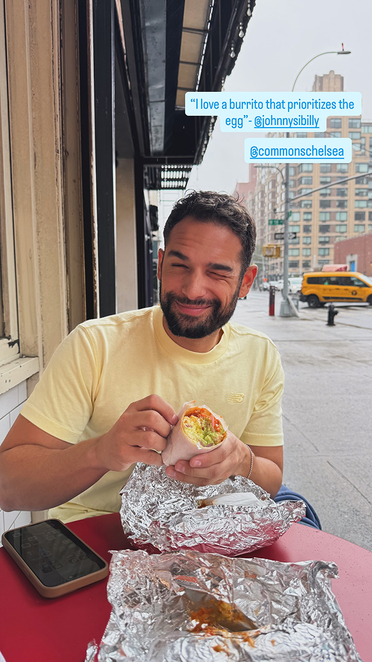 Influencer Ian Paget easting a breakfast burrito from Commons Chelsea sitting at a table outside in Chelsea Manhattan
