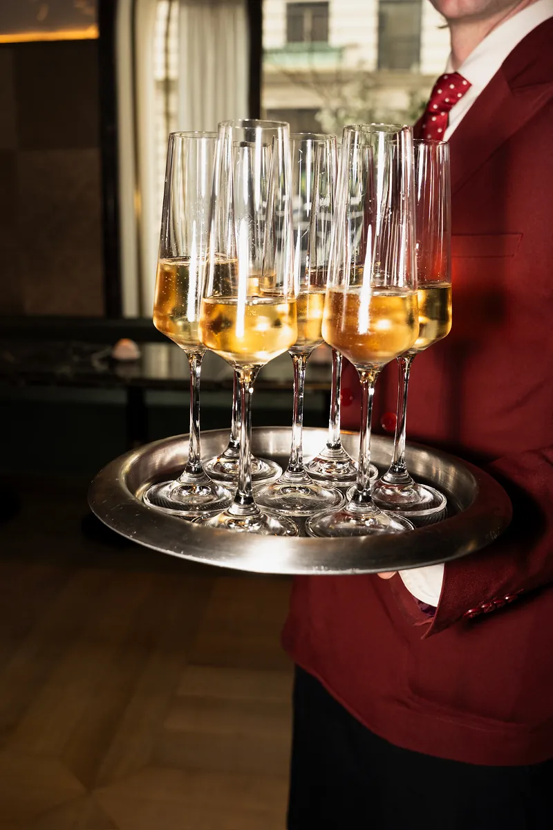 Server holding a tray of champagne glasses during Beefbar NYC’s 2-year anniversary celebration with Storytime creators and casino night experiences