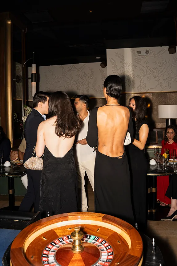 Guests and Storytime creators socializing beside a roulette table during Beefbar NYC’s 2-year anniversary casino night celebration in Manhattan.
